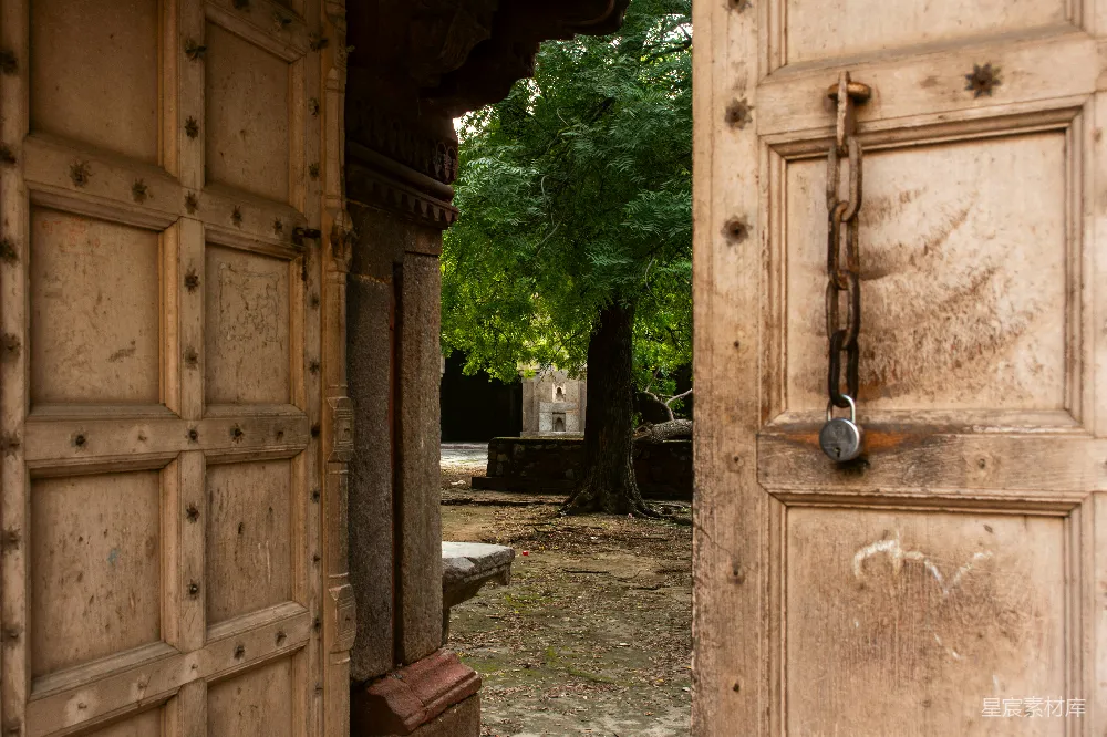 高清摄影  推开木门，露出了一个庭院，庭院里有树木。