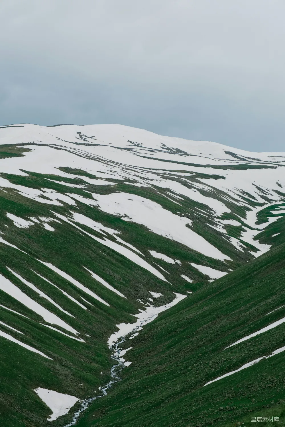 覆盖着白雪的山峦与绿色草地共存