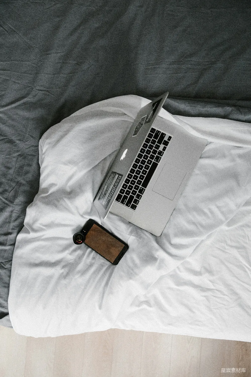 高清摄影  MacBook Pro 放在棕色皮质钱包旁边，放在白色的床上。