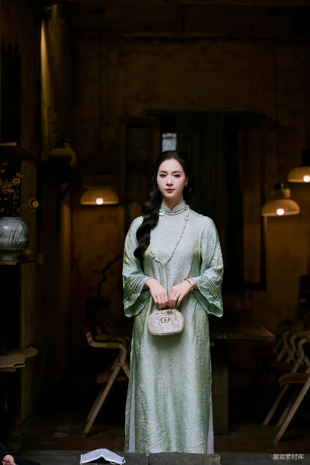 高清摄影  穿着浅绿色的传统连衣裙的女士手里拿着一个钱包。