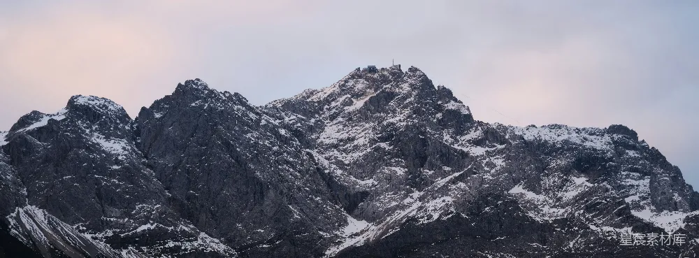 山被雪覆盖，天空中几朵云。