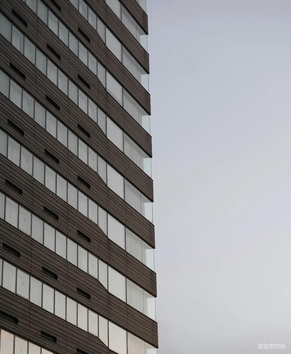 高清摄影  现代建筑立面，带有重复的窗户和深色面板。