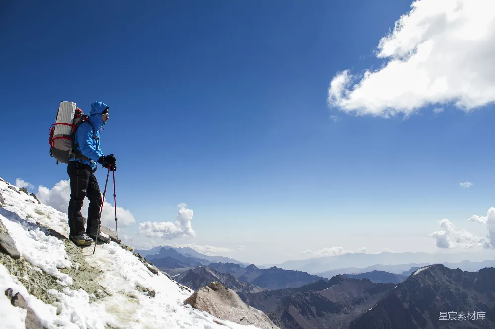 背着背包的男人正在雪山上徒步前行。