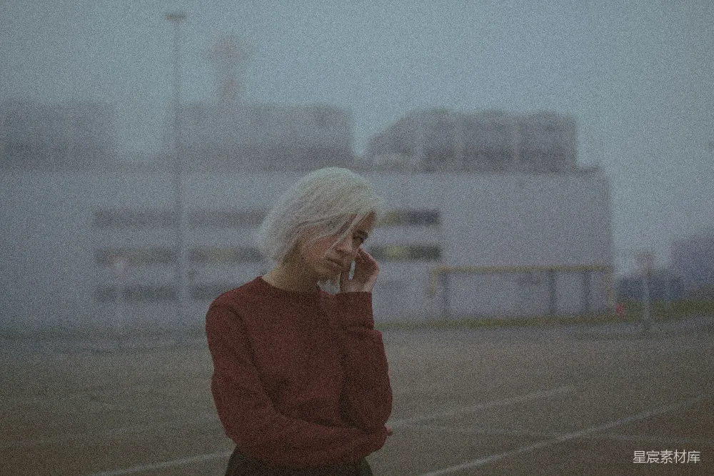 红色毛衣的女人在灰泥地板上站立，白天的场景