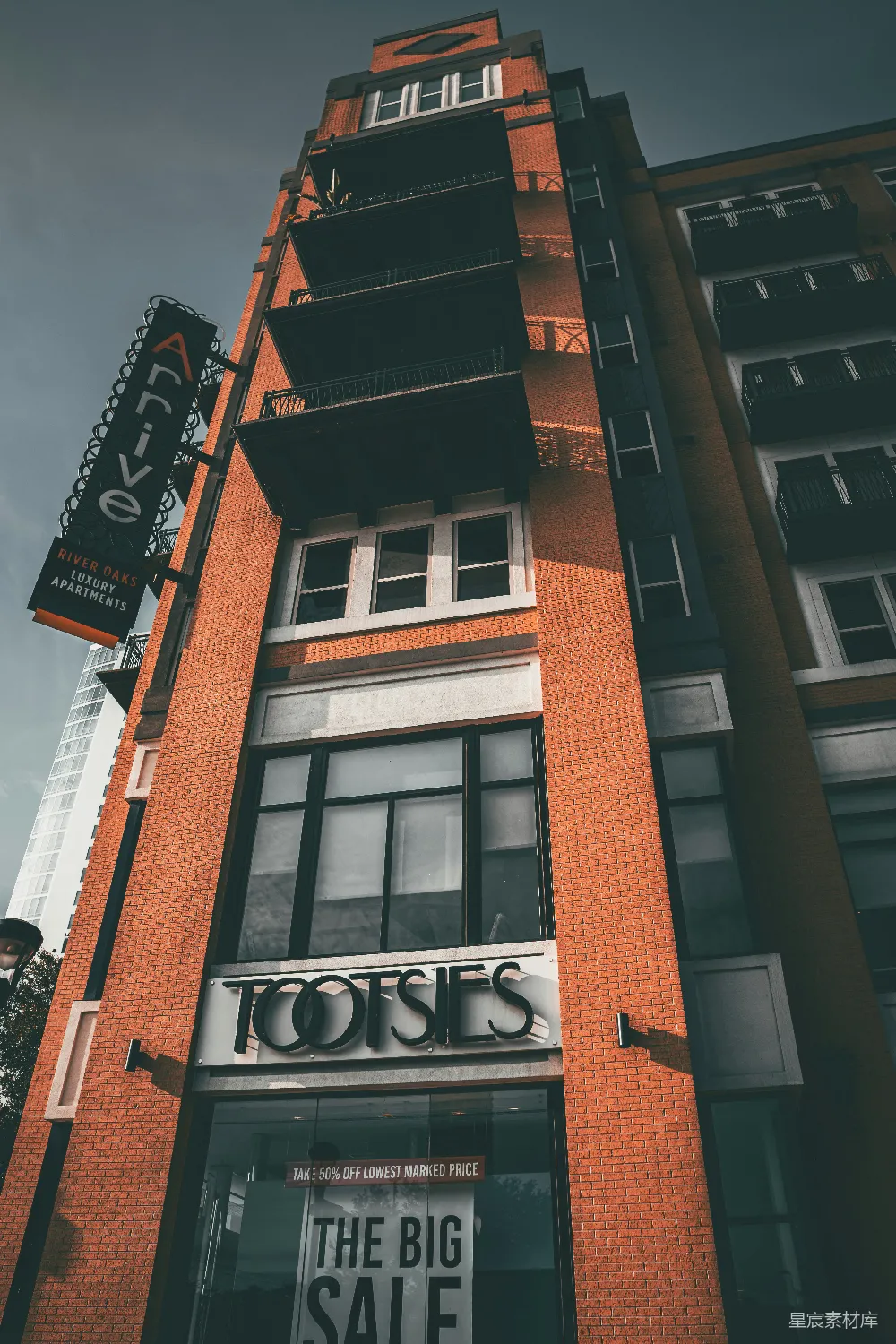 高清摄影  一座高大的砖砌建筑，上面有“tootsies”和“arrive”的标志。