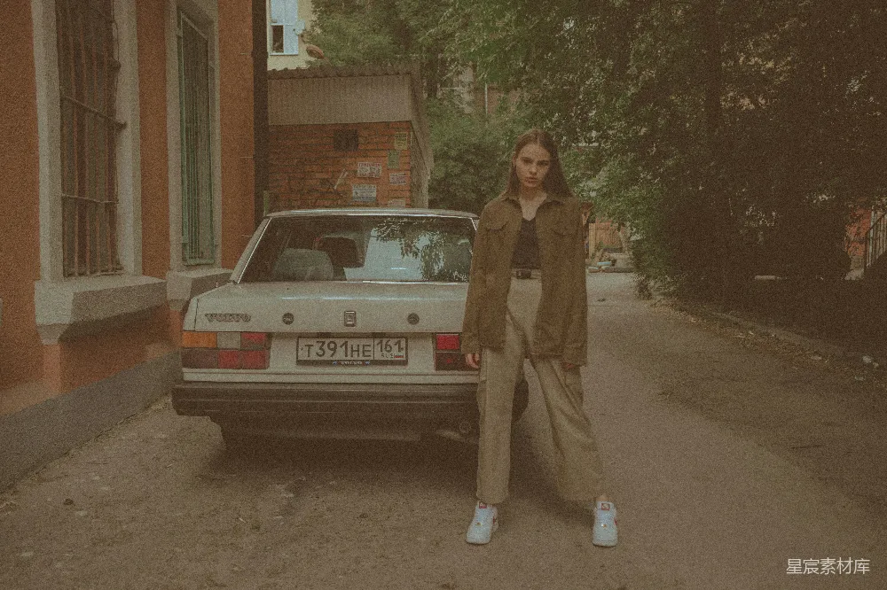 一个女人站在一辆古董车前。