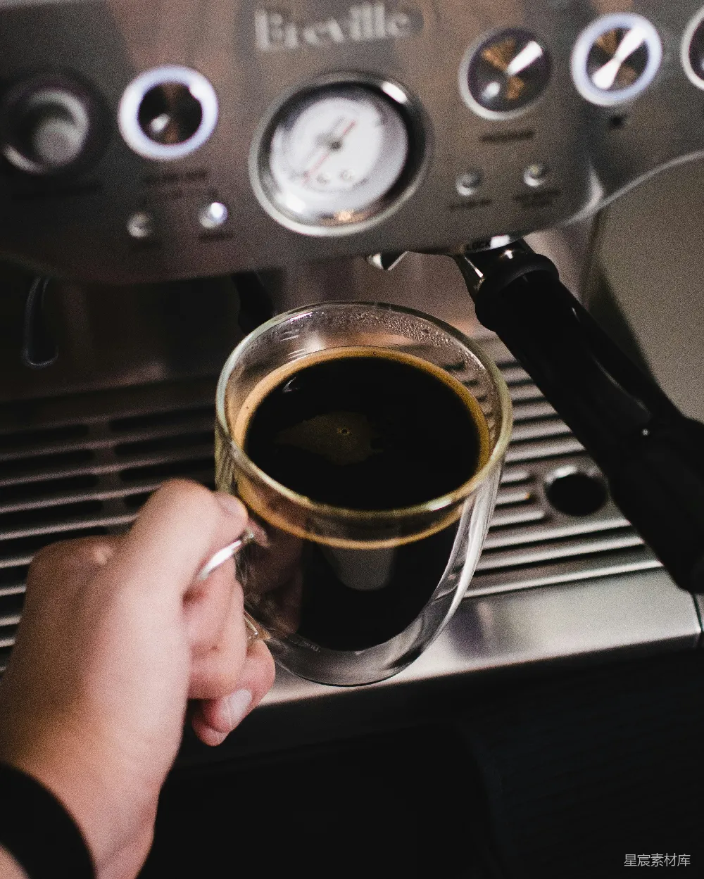 手持透明玻璃杯的人举着一杯棕色液体