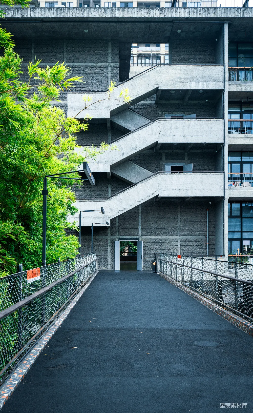 高清摄影  混凝土建筑，带有室外楼梯和绿色树木。