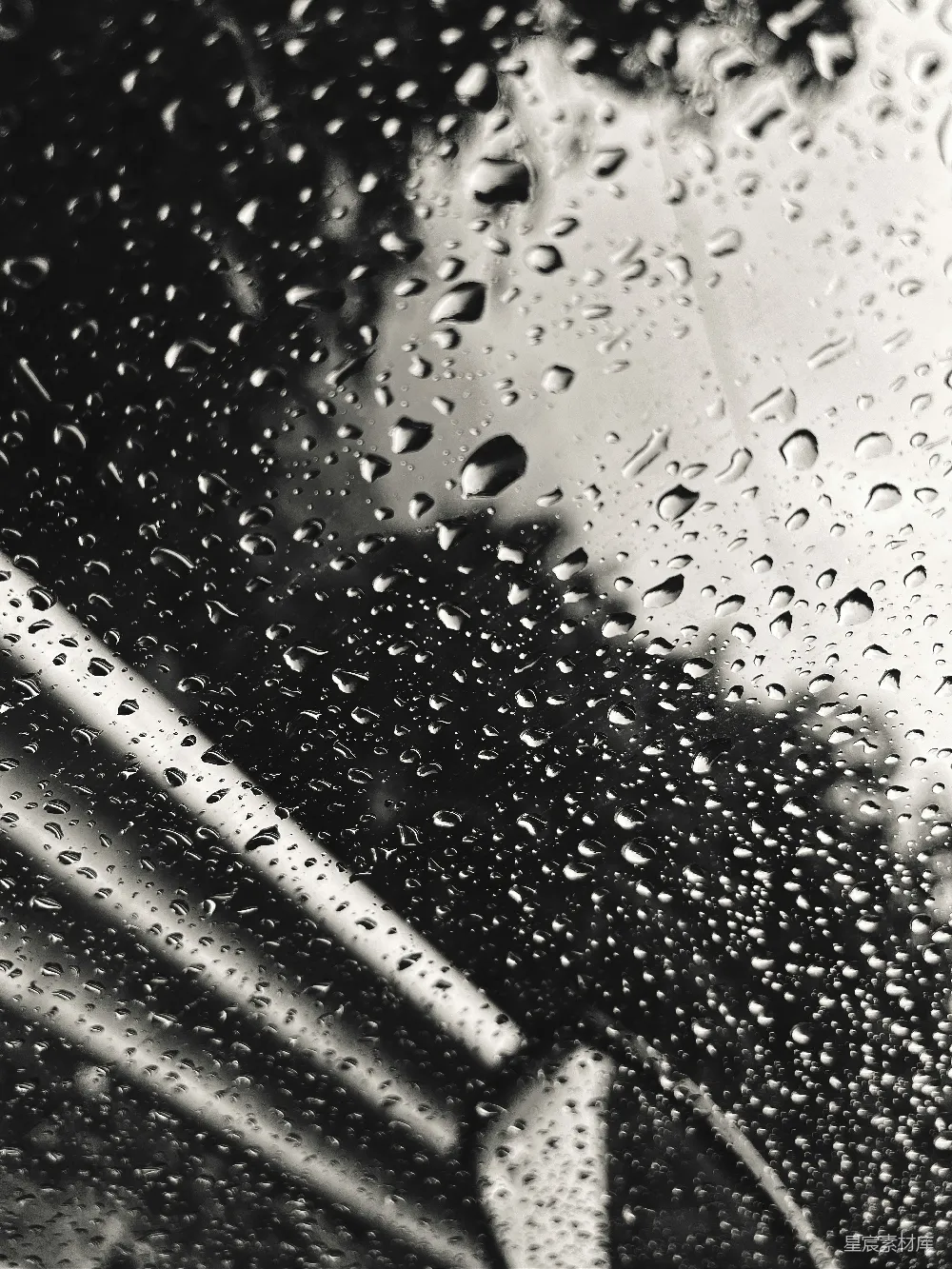 一幅黑白照片中的雨滴落在窗户上