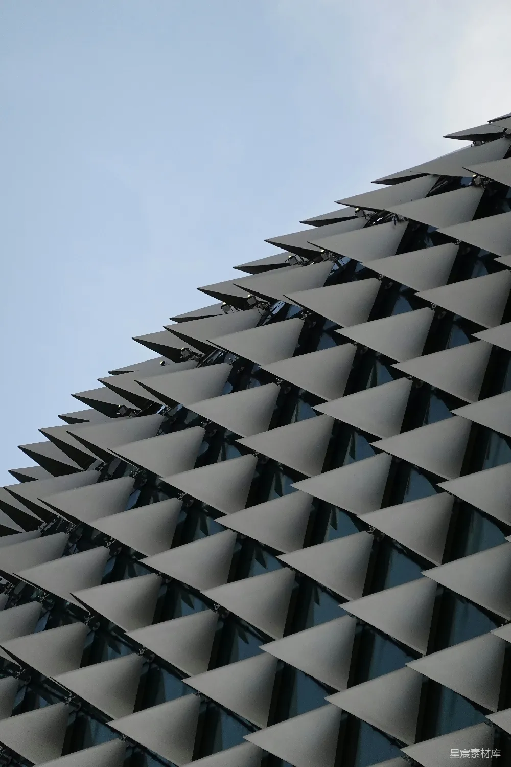 高清摄影  现代建筑外墙上的重复三角形图案与蓝天相对。