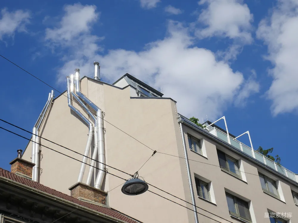 高清摄影  建筑物外墙上的闪亮金属管道在蓝天背景下。