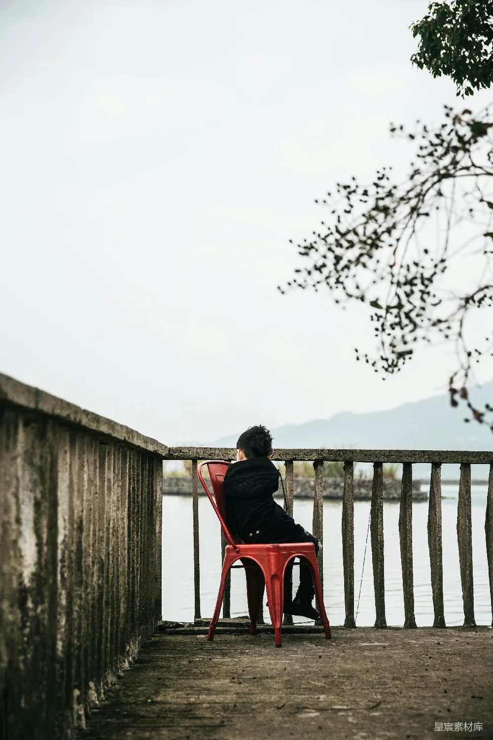 高清摄影  坐在栏杆旁边的无靠背椅上的男孩
