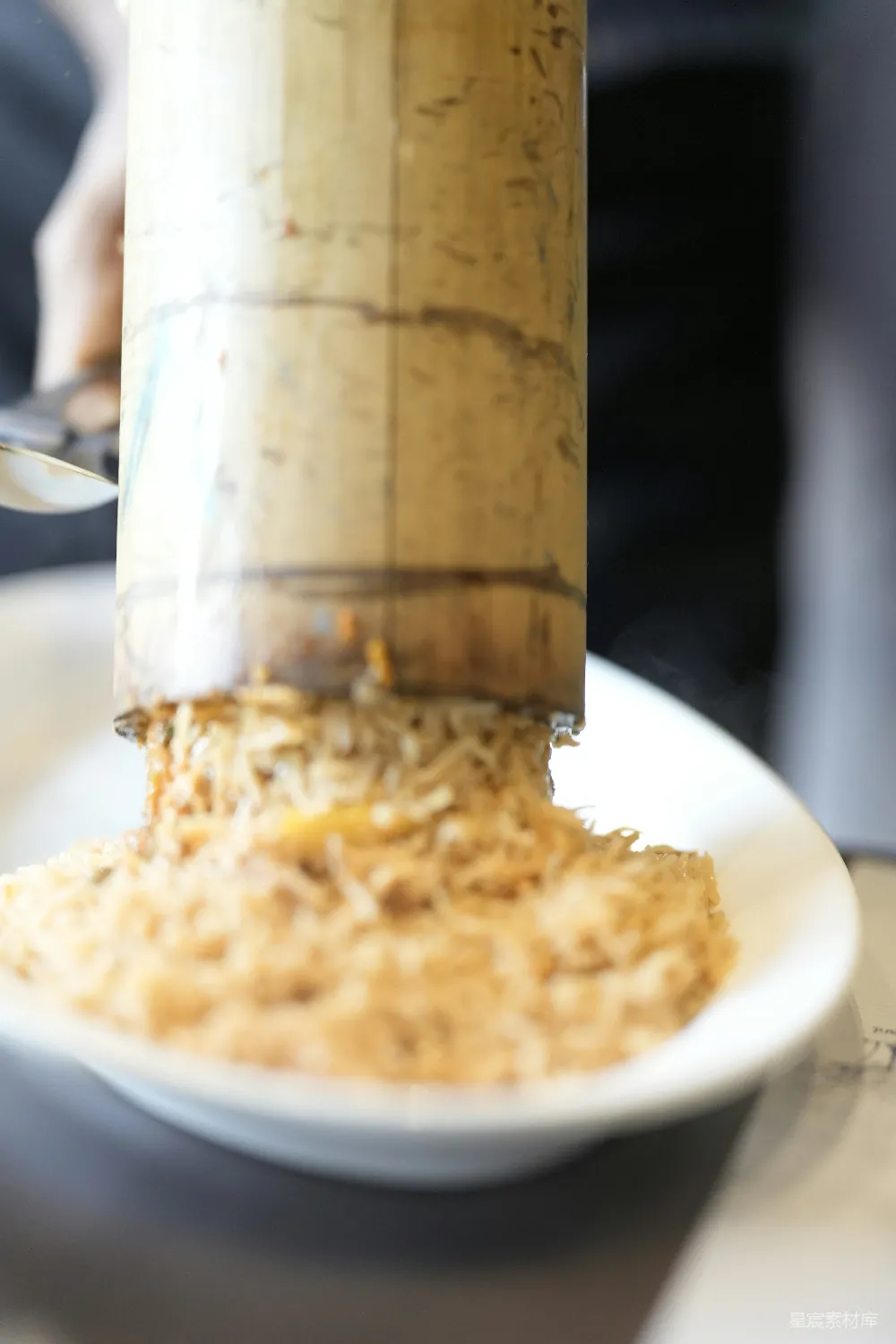 煮好的米饭正从竹管中 dispensing。