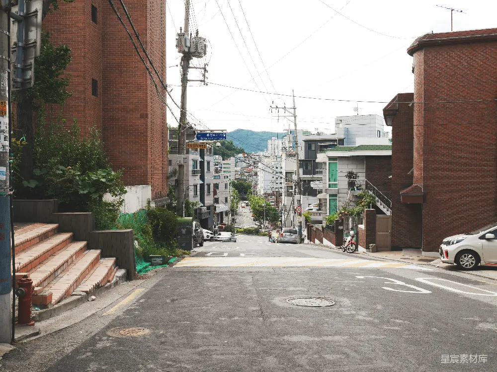 高清摄影  白天间，灰色水泥路夹在棕色水泥建筑之间。