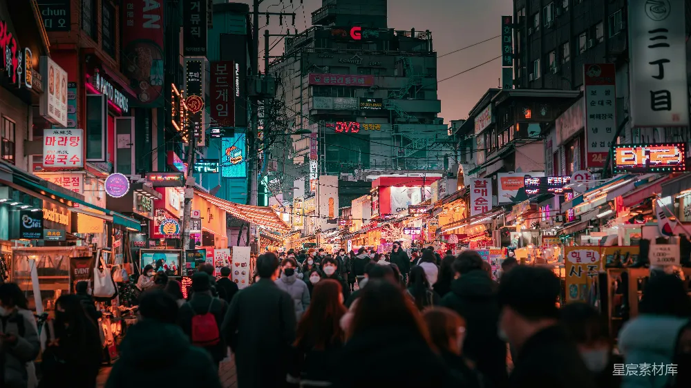 高清摄影  一群人沿着街道行走，旁边是高楼大厦。