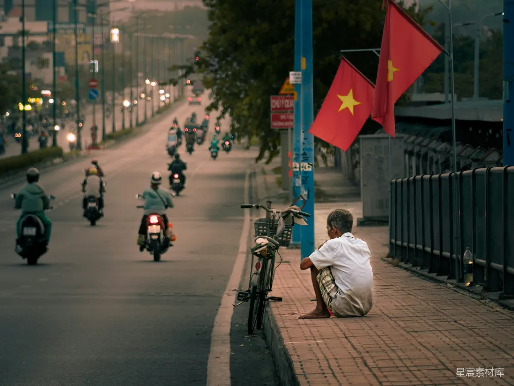 高清摄影  一个男人坐在路边，旁边有一辆摩托车。