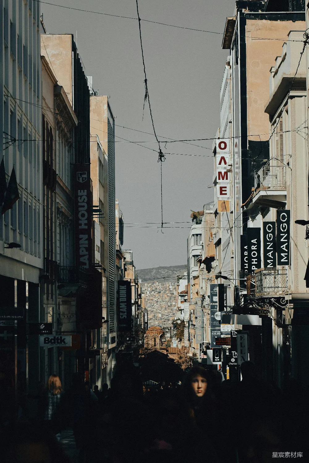 高清摄影 旅行 一群人沿着街道行走，两旁是高大的建筑物。