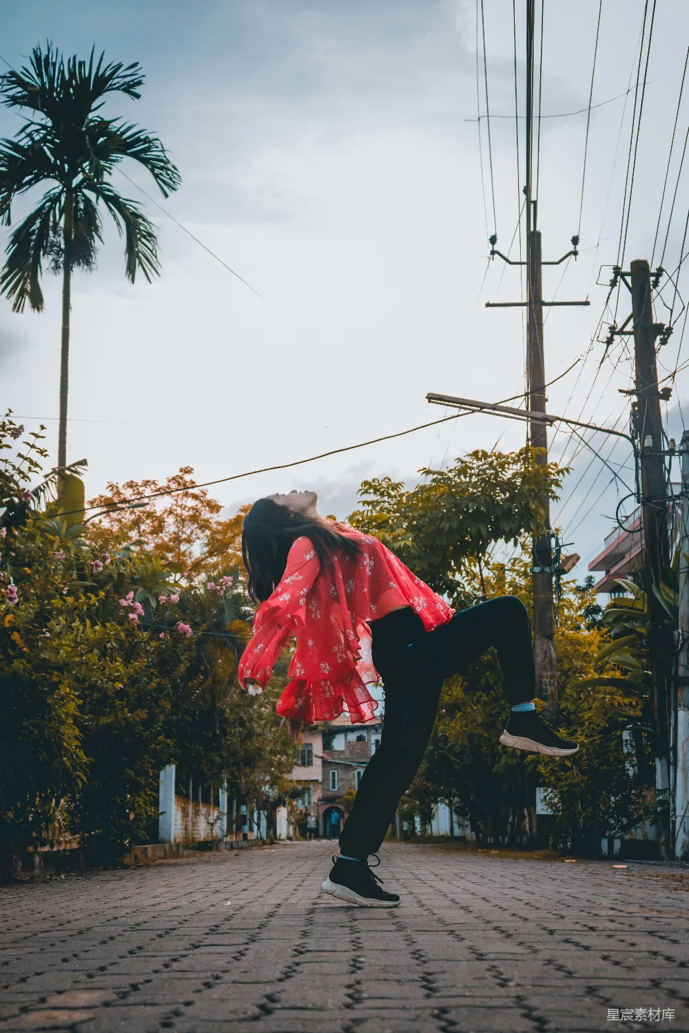 高清摄影  穿着红色衬衫和黑色裤子的女人白天在街上跳跃。