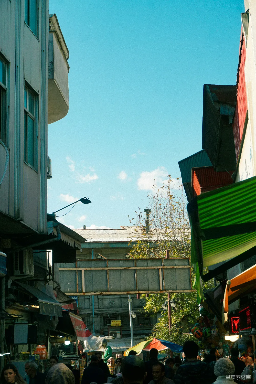 高清摄影  繁忙的街头市场，周围有建筑物，天空湛蓝。