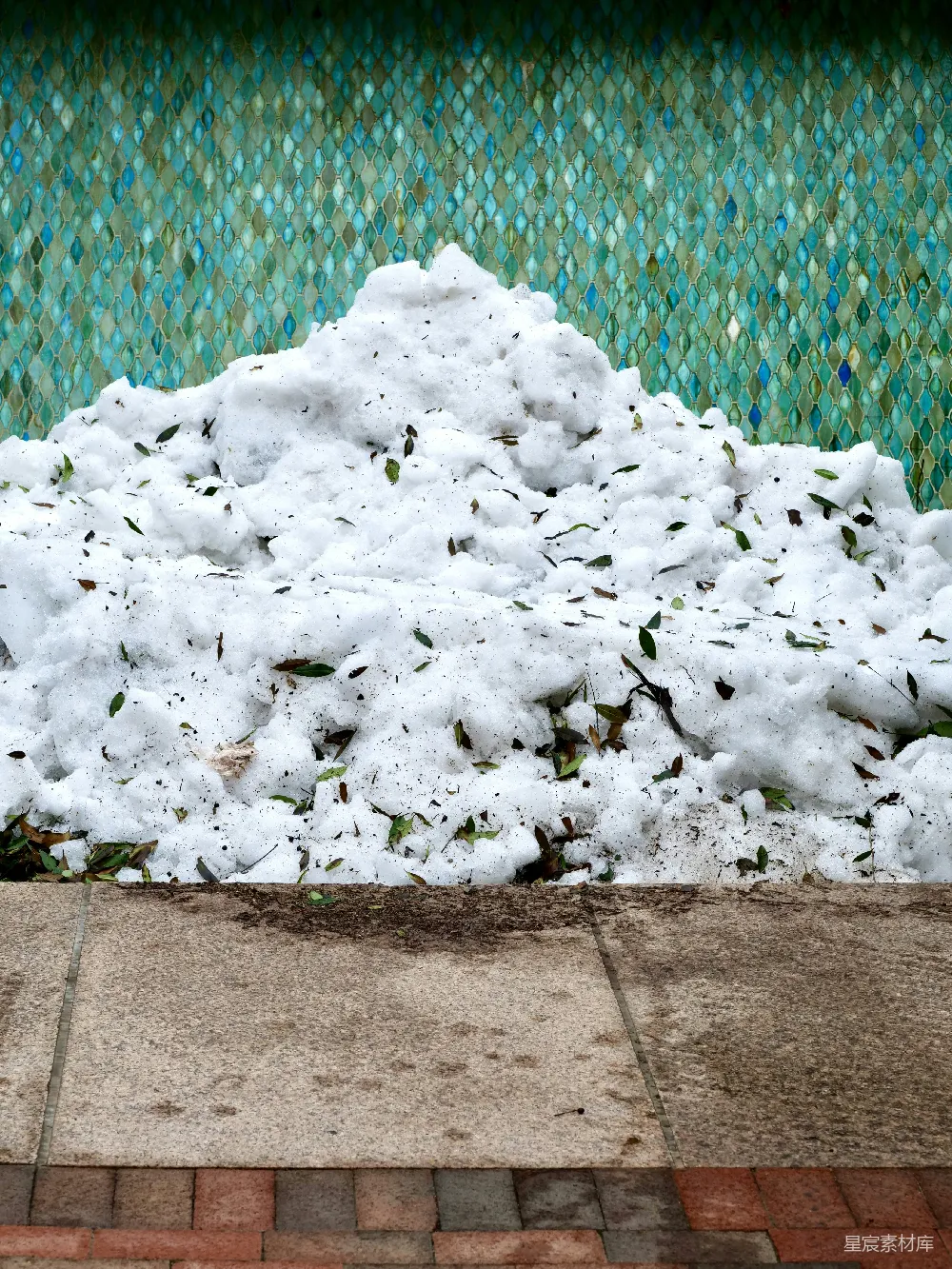 一大堆雪堆积在瓦墙旁。