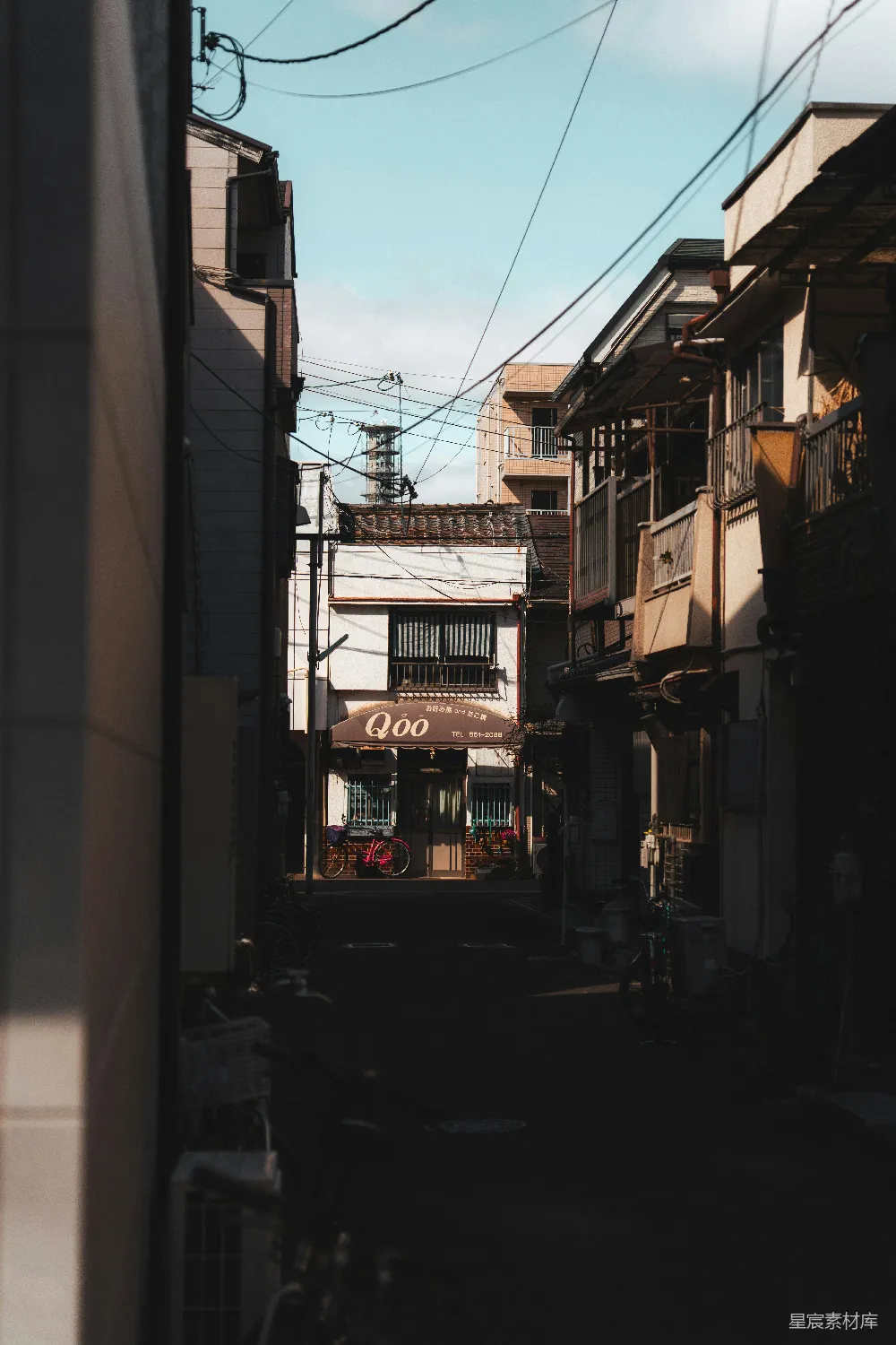 高清摄影  狭窄的城市小巷，两旁是建筑物和头顶上的电线。