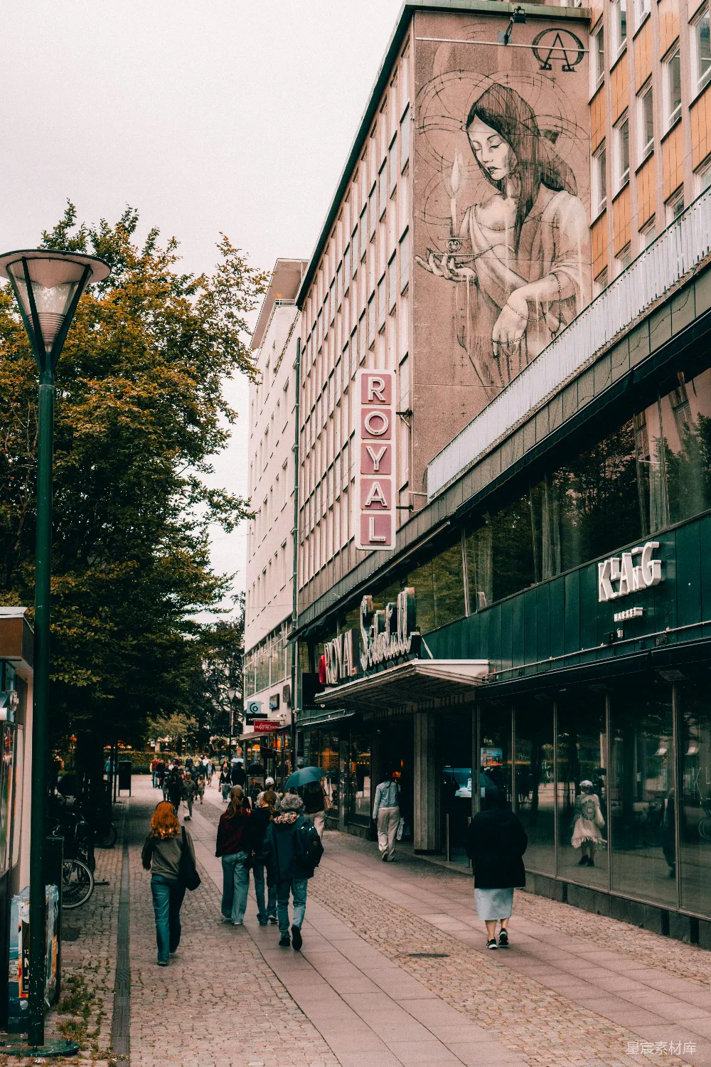 高清摄影  一群人沿着街道走着，两旁是高大的建筑。
