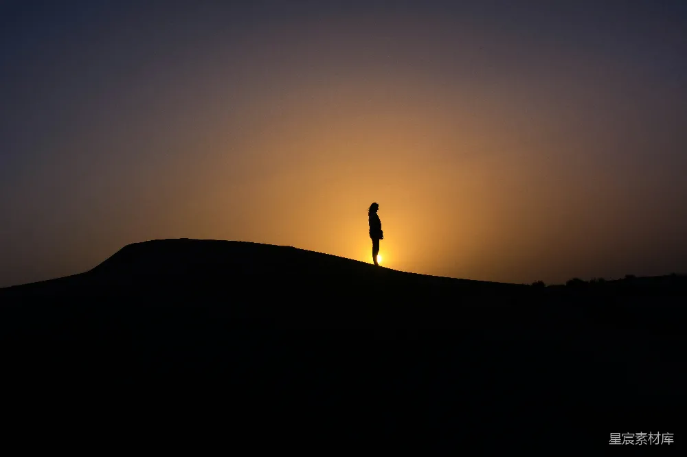 山头站立人的 silhouette 在夕阳西下时的景象