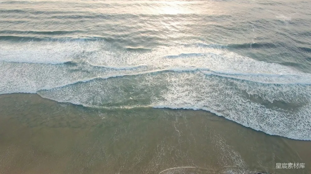 海滩上空俯视的景象，海浪涌来