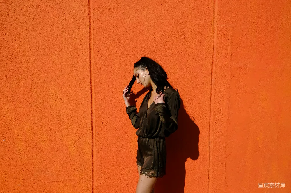 女人靠近橙色的墙