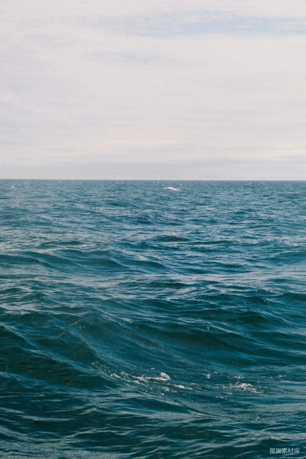 深蓝海洋波涛 beneath 乌云密布的天空