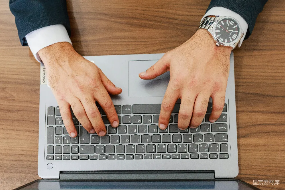 一个人在桌面上打字的笔记本电脑前 typing。