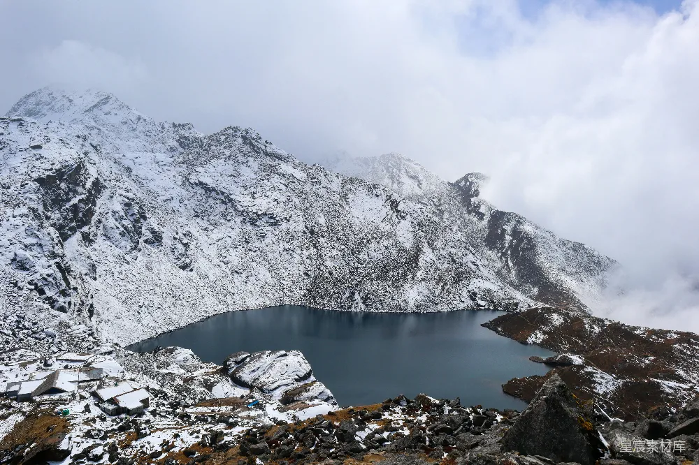 覆盖着白雪的山峦，湖水周围环绕着岩石。