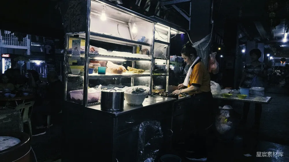 夜市摊位上的售卖者准备食物。