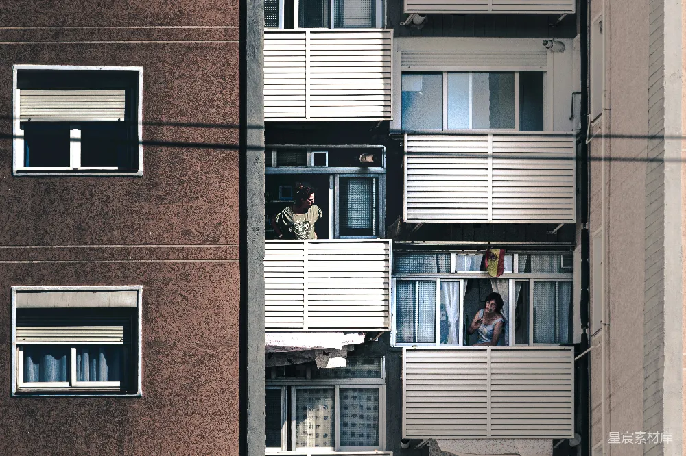 黑色夹克的男人站在棕色砖砌建筑旁