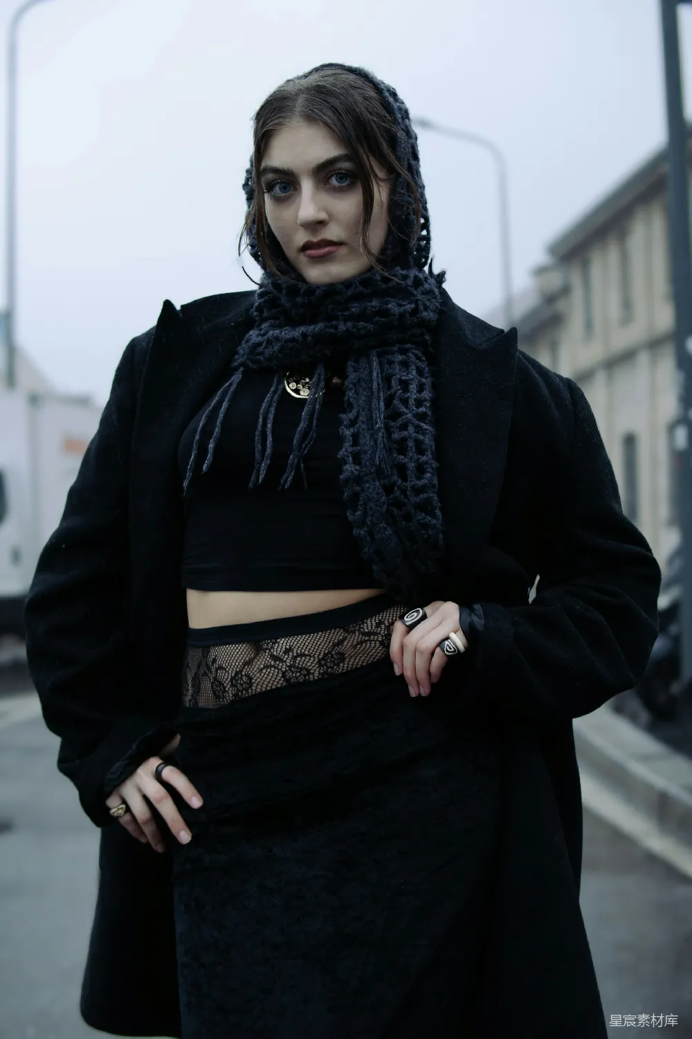 一位妇女站在街角，穿着黑色 outfits。