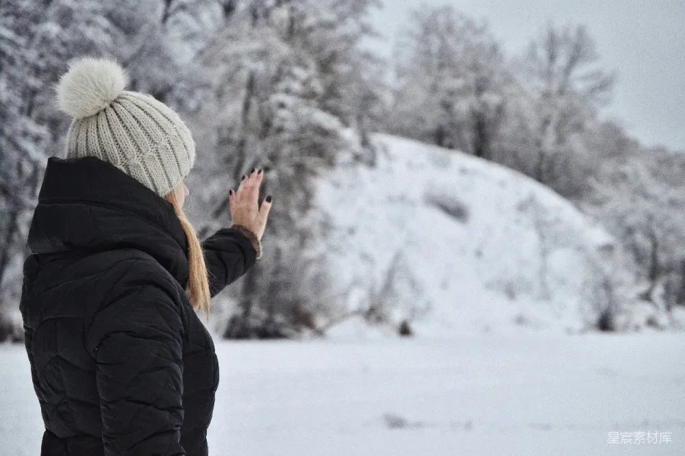 高清摄影 人物 一个女人站在雪中看着她的手机。