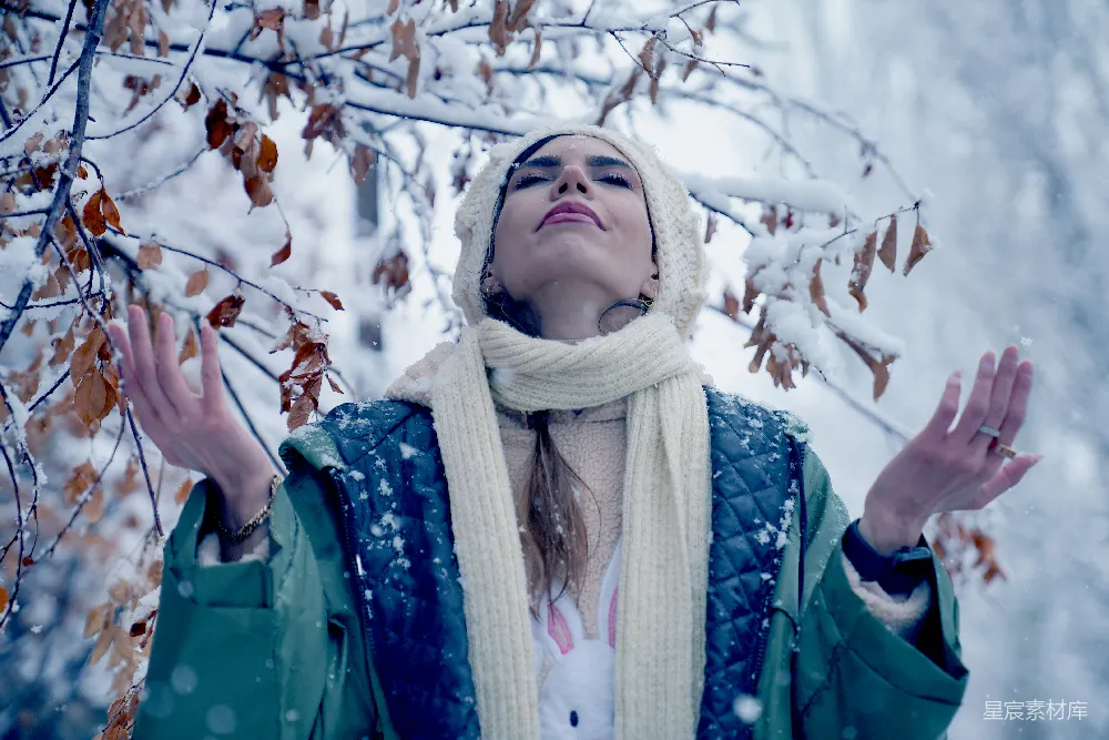 高清摄影  一位女士站在一棵被雪覆盖的树前。