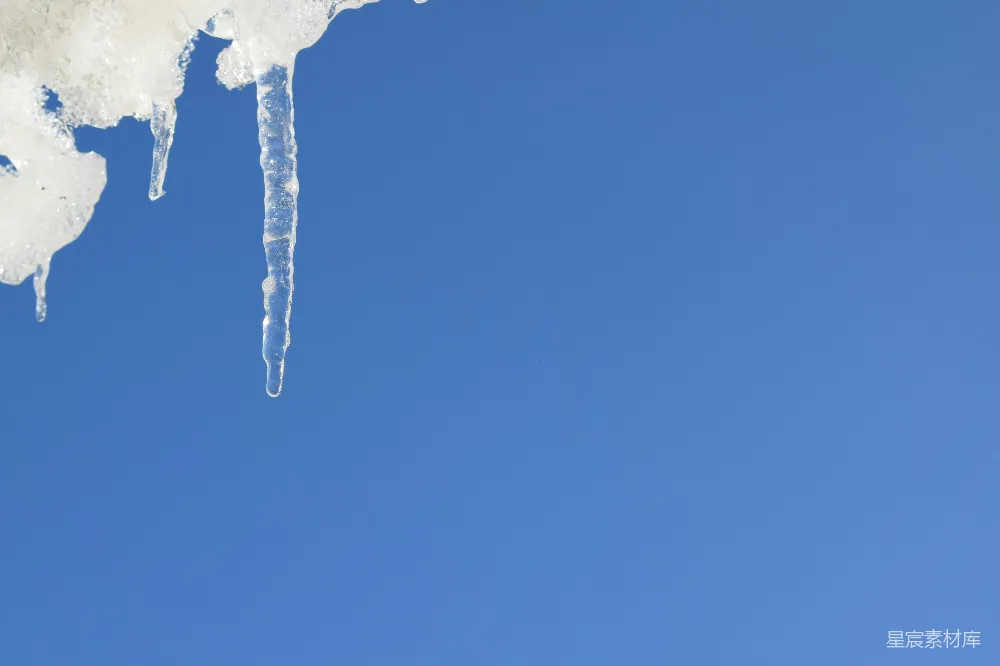 高清摄影  冰凌挂在雪地上，背景是明亮的蓝天。