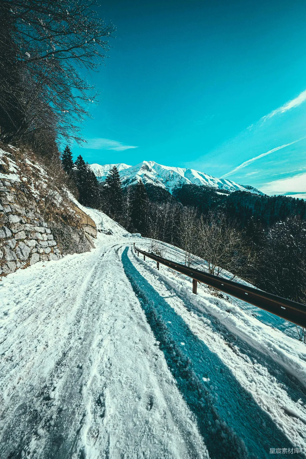 高清摄影  白天蓝天下，树木间的积雪覆盖的道路