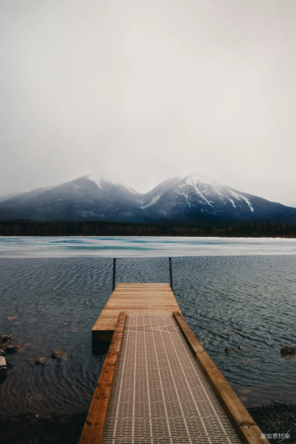码头旁边有一片湖泊，山峦在背景中。