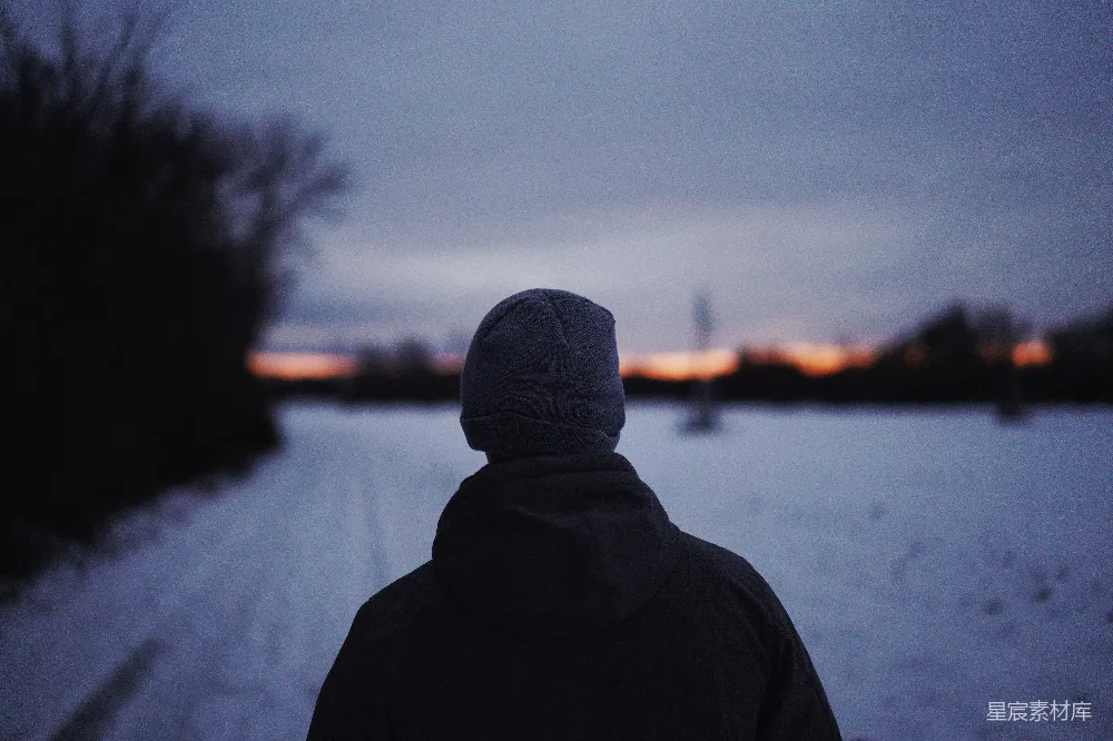高清摄影 人物 穿黑色连帽衫的人站在雪覆盖的田野旁边，白天。