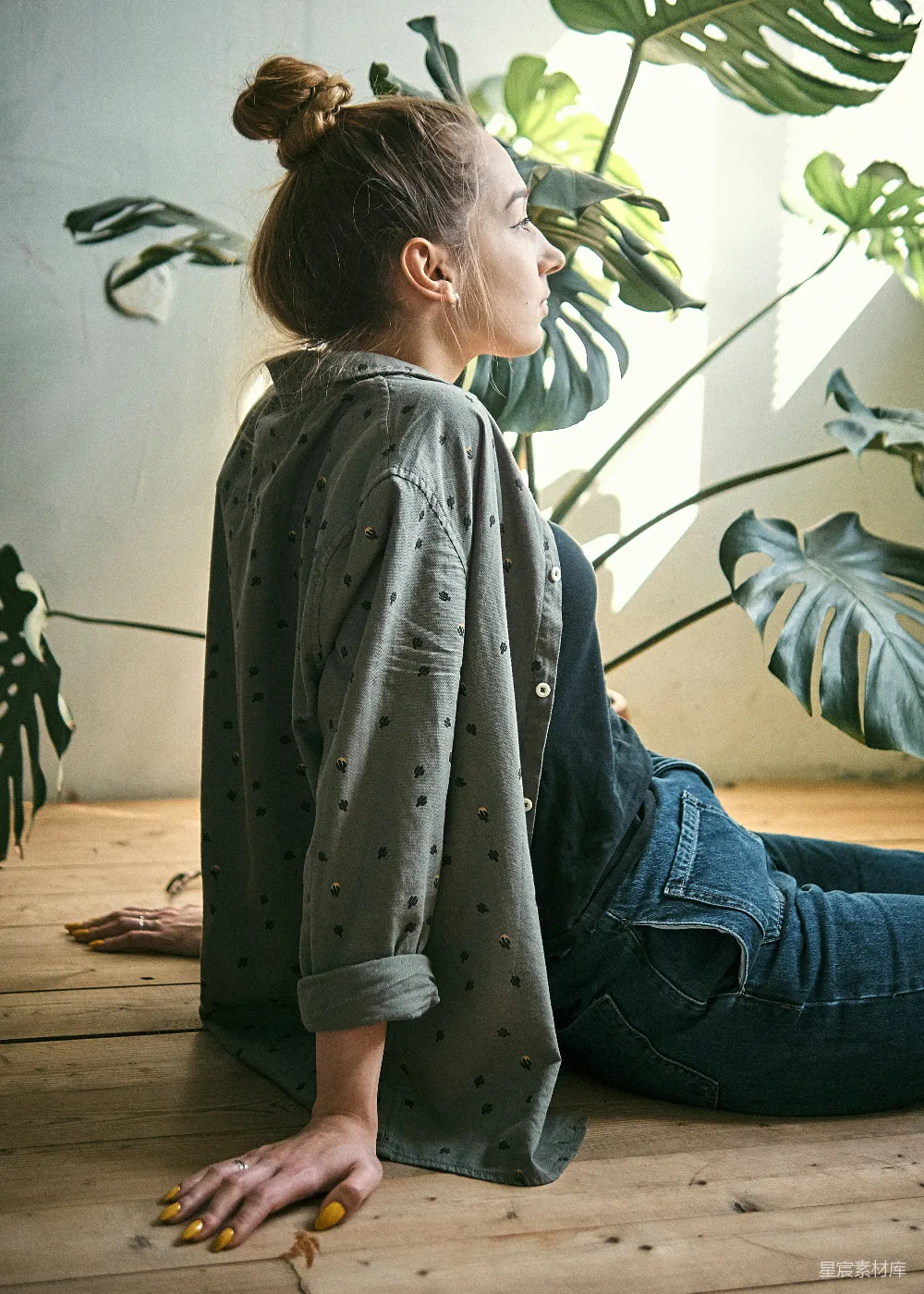 灰T恤和蓝色牛仔裤的女人坐在棕色木制地板上