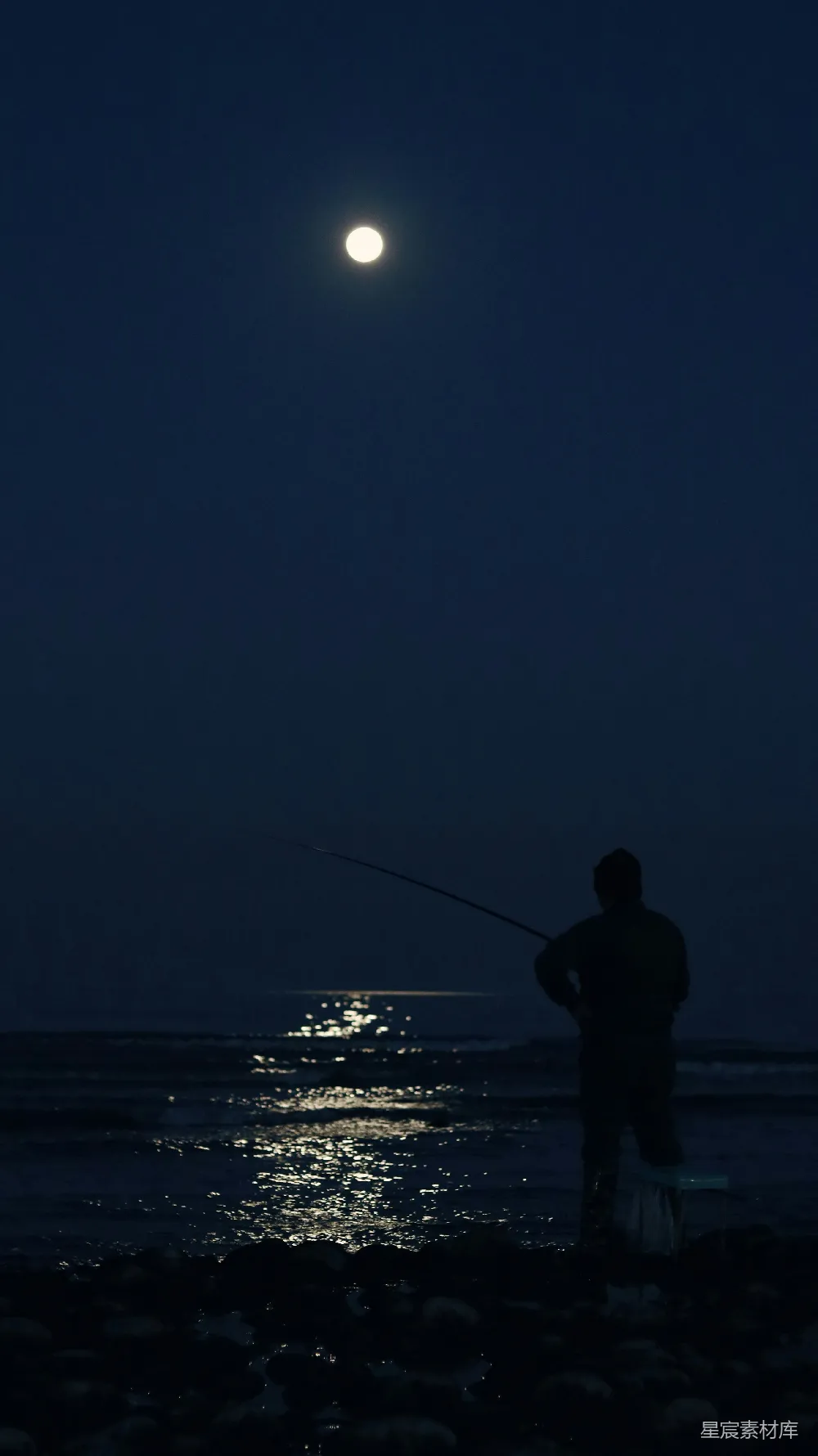 高清摄影  一个男人在夜间在海滩上钓鱼。