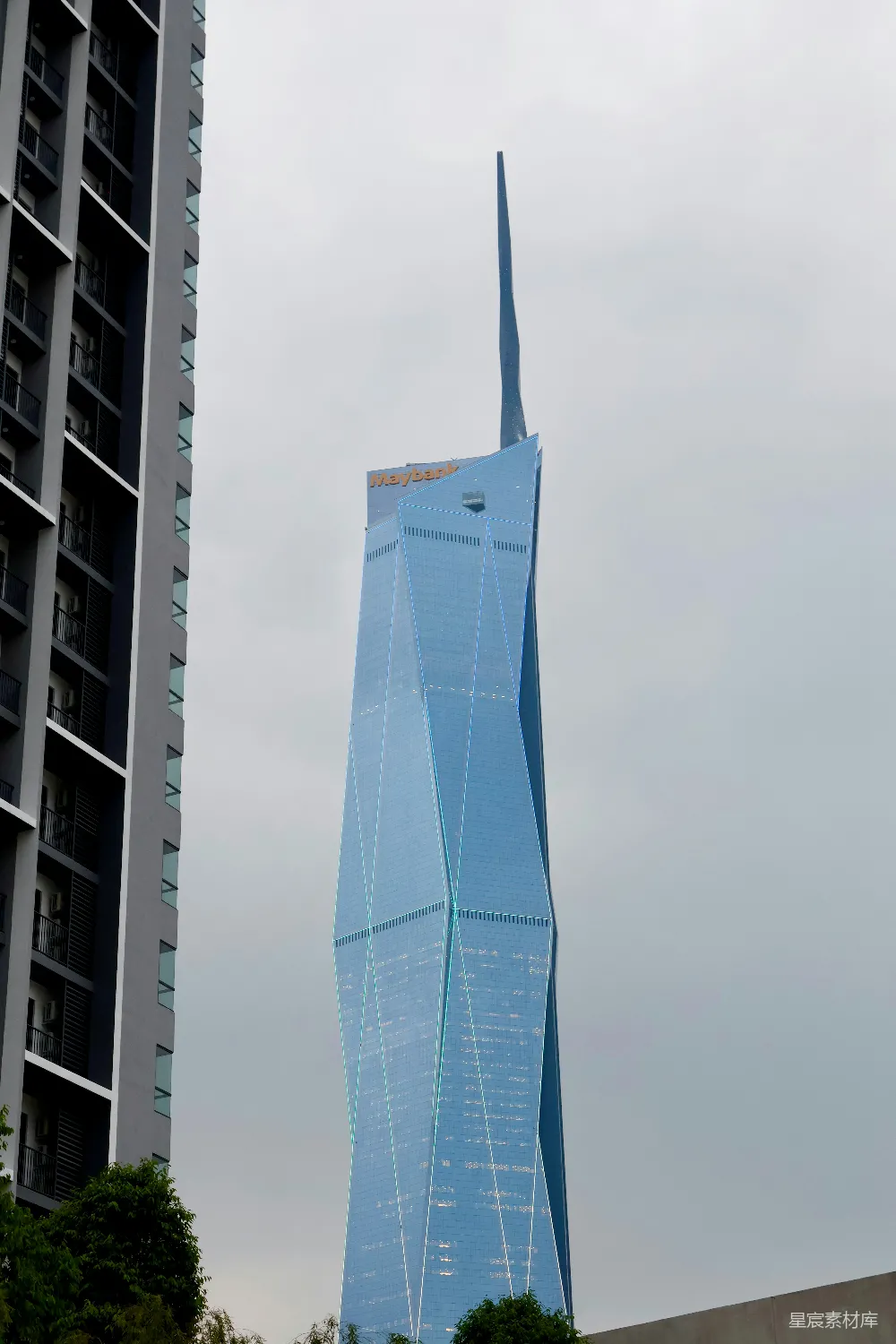 高耸的现代蓝色摩天大楼及其旁边的建筑在阴云密布的天空下。