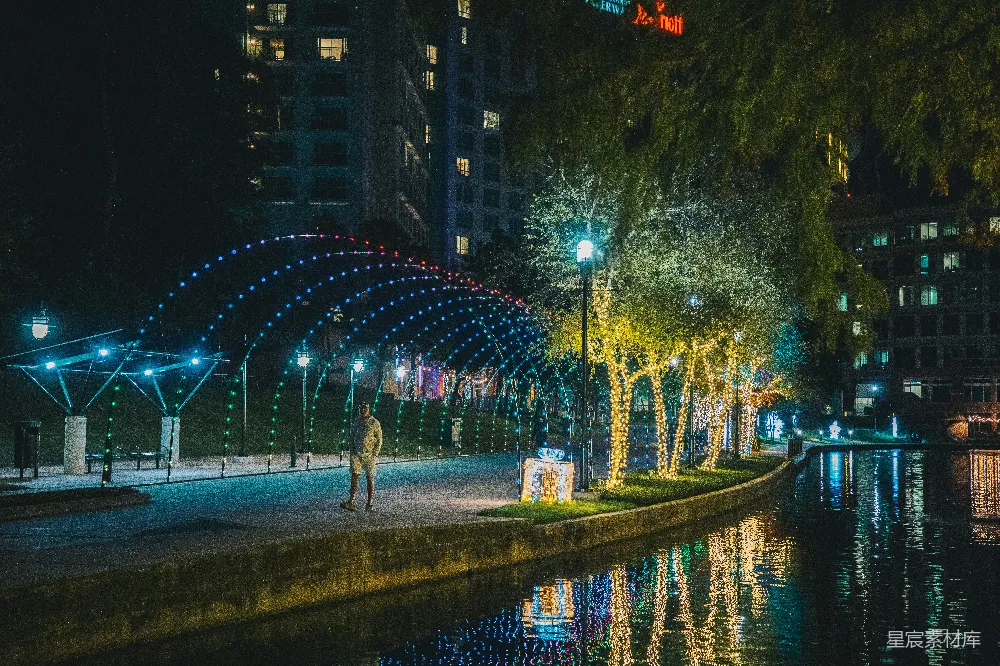 高清摄影  一个男人在夜晚沿着河边的街道行走。