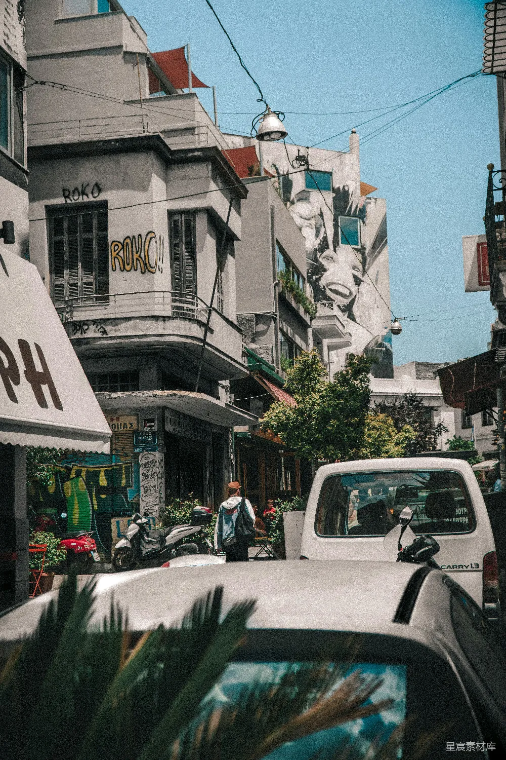 一辆卡车沿街行驶，旁边是高大的建筑物。