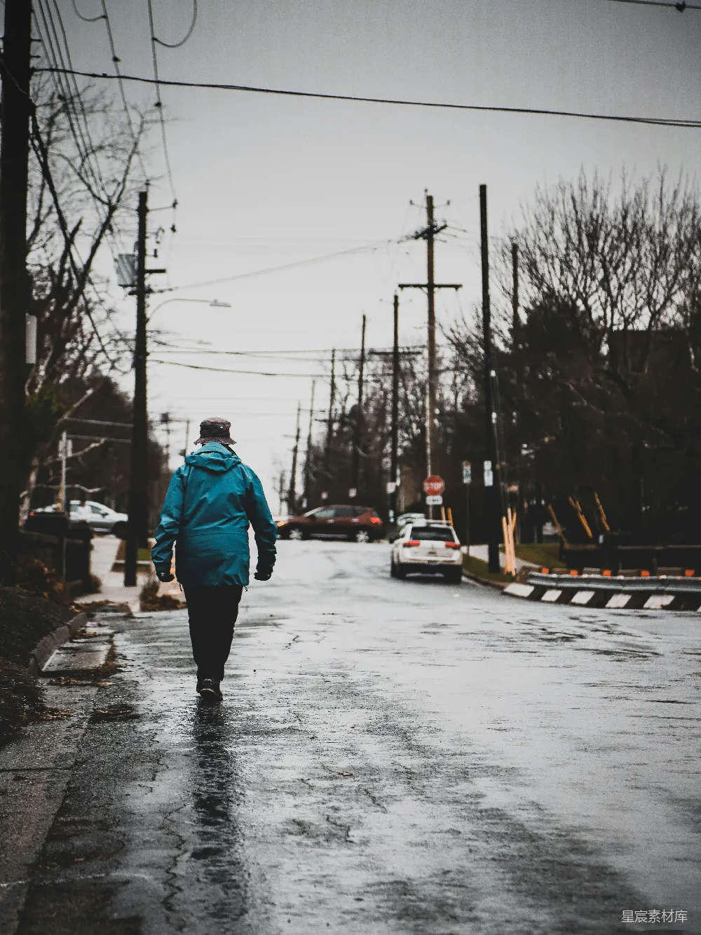 穿着蓝夹克的男人在雪覆盖的小路上白天行走