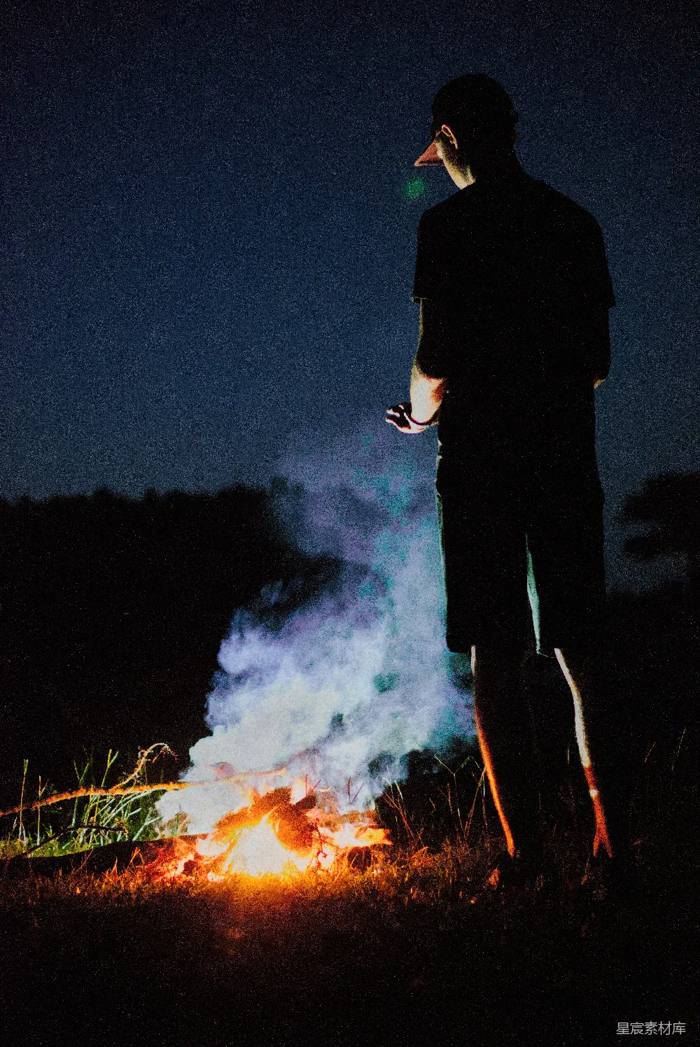 一个男人站在夜晚的火堆前