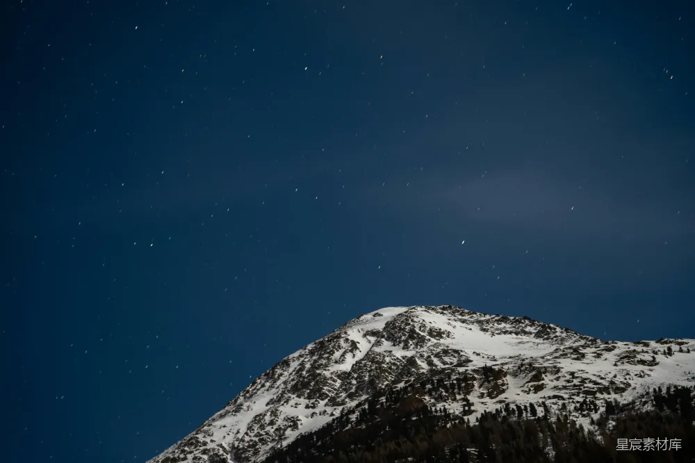 覆盖着白雪的山峦在深蓝色的天空下。