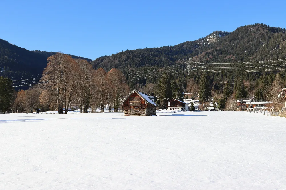 背景有一座房子的覆盖着白雪的田野